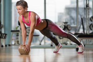 Attractive Female Athlete Performing Push-Ups On Medicine Ball